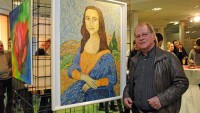 Der Kunstmaler Jörg Christian steht neben einem Gemälde, das die Mona Lisa zeigt.