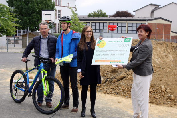 Madeleine Möller von der AOK Hessen überreicht einen großen Scheck an die Schulleiterin. Mit dabei: Markus Brüx von NEON und Michael Schipper von Bikepool. Foto: Traudi Schlitt