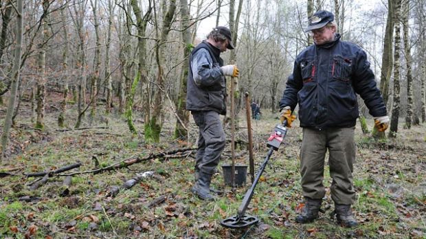 Mann mit Metallsonde in einem kahlen Wald