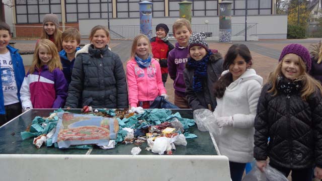 Eine Gruppe von Kindern steht um einen Tisch voller Unrat zusammen.